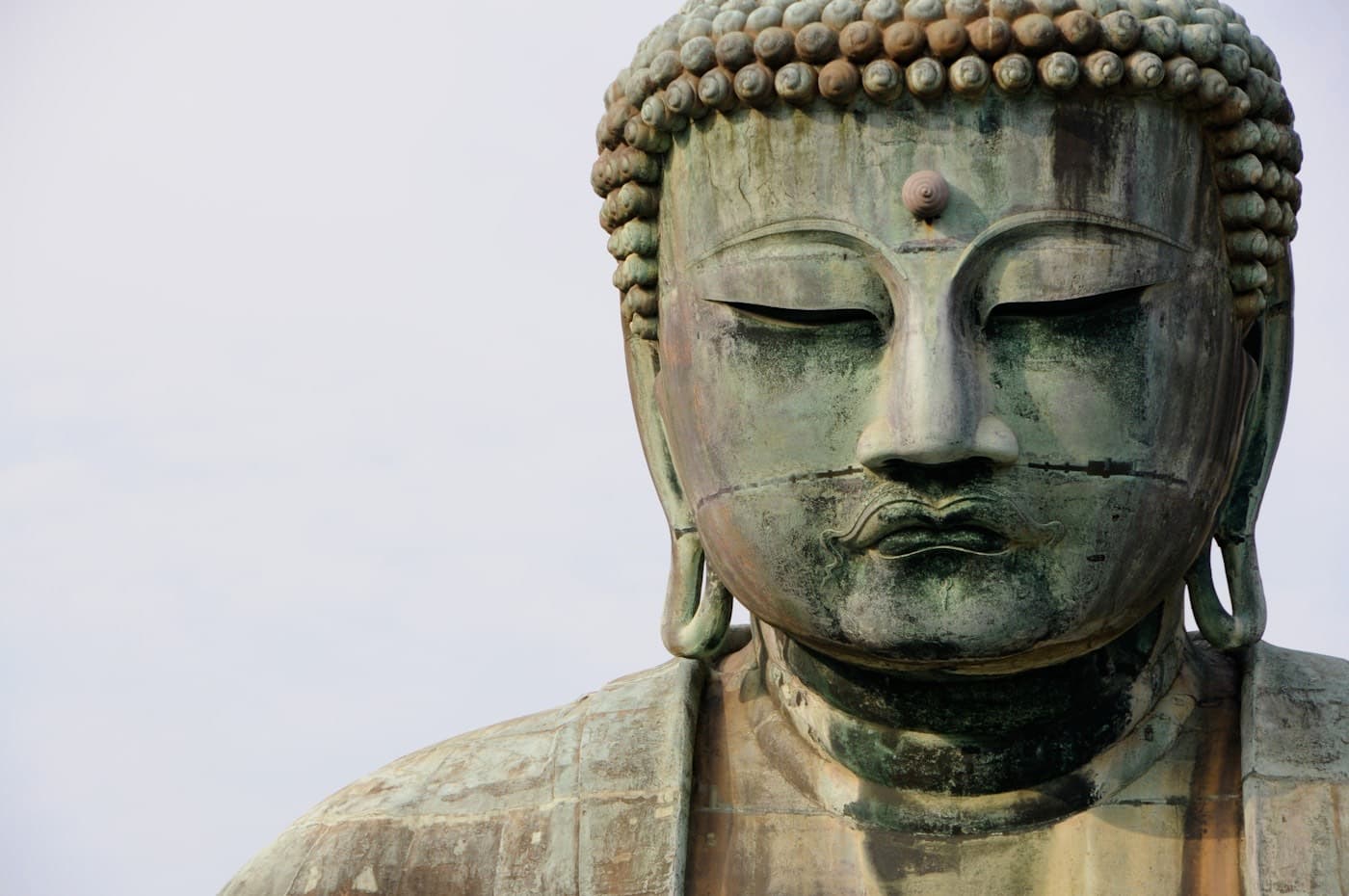 Il volto del Grande Buddha di bronzo di Kamakura, con la patina verde e gli occhi socchiusi