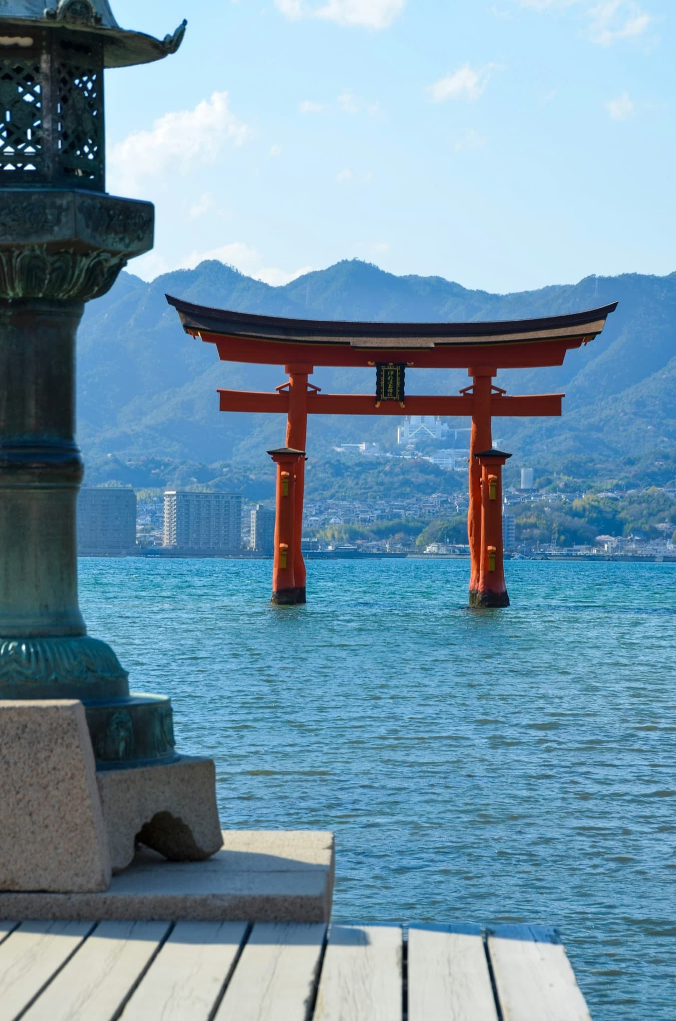 Il grande torii rosso di Miyajima che si erge sul mare, con le montagne sullo sfondo