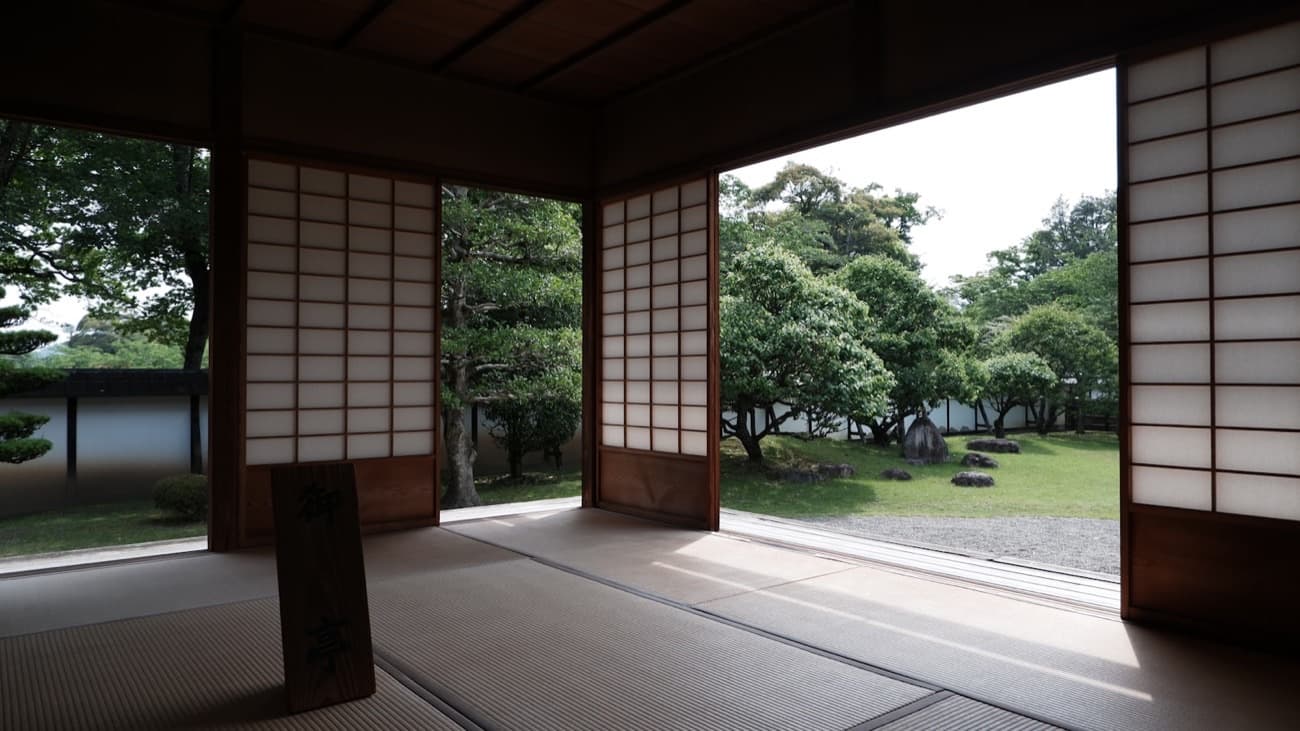 Una stanza in tatami con le porte scorrevoli di carta aperte su un giardino giapponese curato