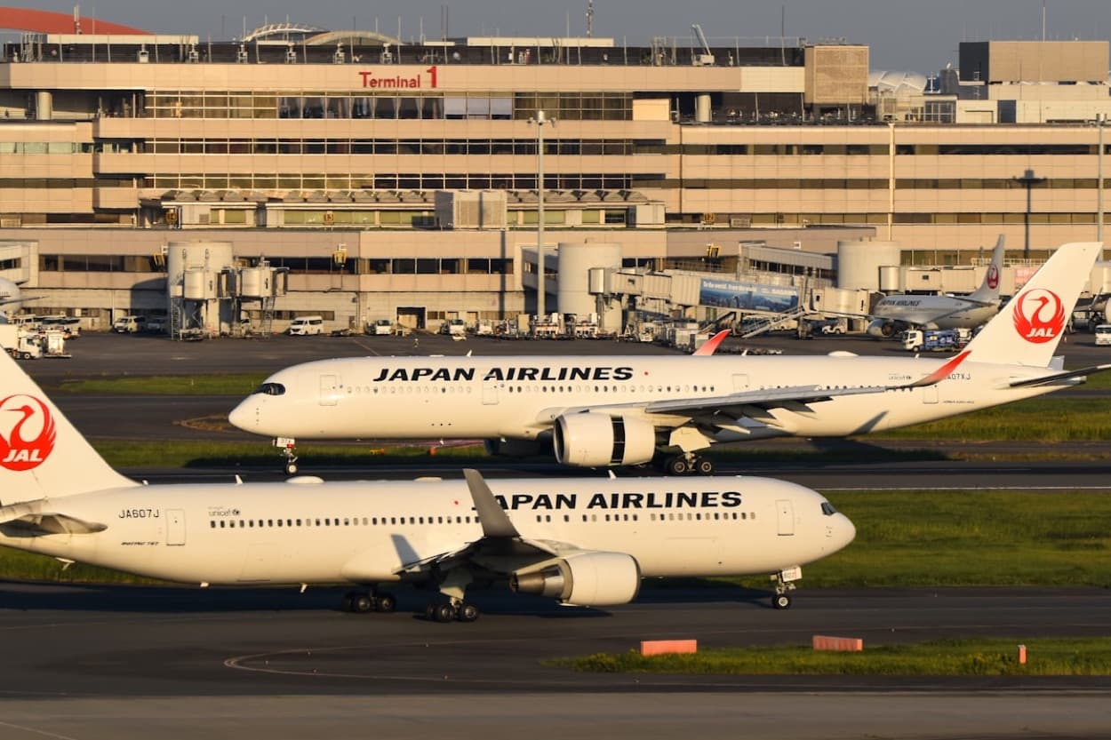 Due aerei di Japan Airlines sulla pista davanti al Terminal 1 di un aeroporto giapponese al tramonto