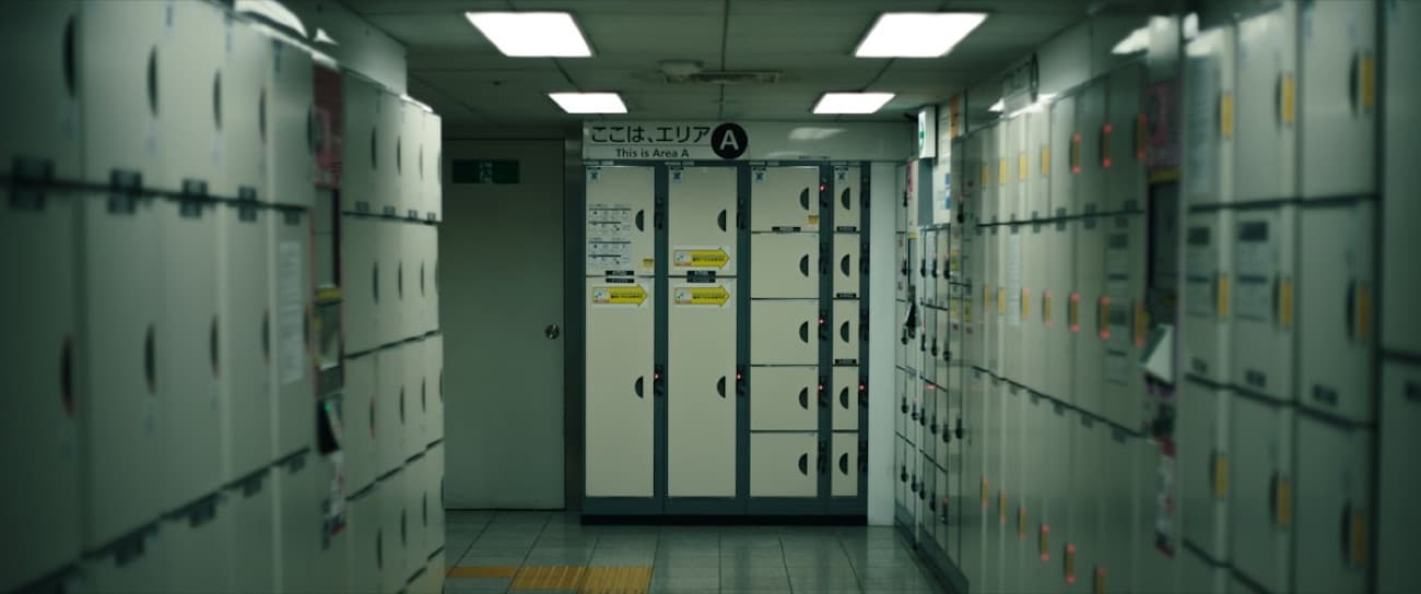 Una fila di coin locker bianchi in una stazione giapponese, con le indicazioni "Area A" in giapponese