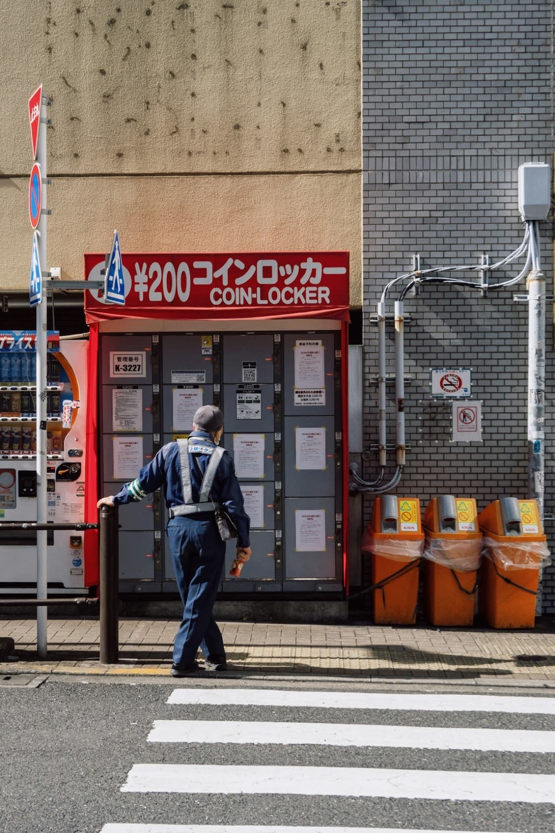 Un coin locker su una strada giapponese con la grande insegna rossa "¥200 コインロッカー COIN-LOCKER"