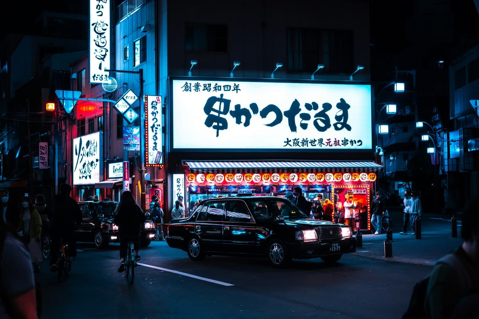 Una strada di Osaka al tramonto, piena di insegne luminose
