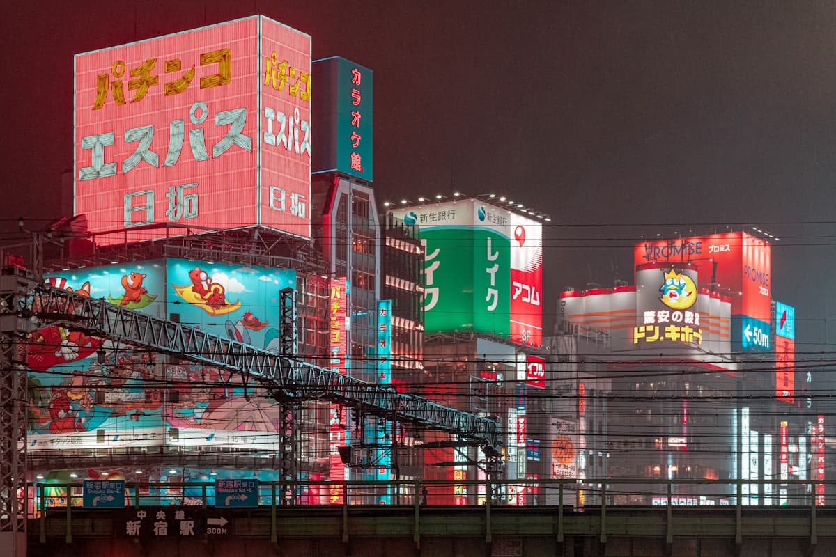 Le insegne al neon di Shinjuku di notte, con il cartello che indica la stazione a 300 metri