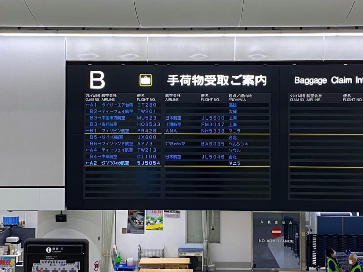 Il tabellone degli arrivi di un aeroporto giapponese, con scritte in giapponese e i nomi delle compagnie