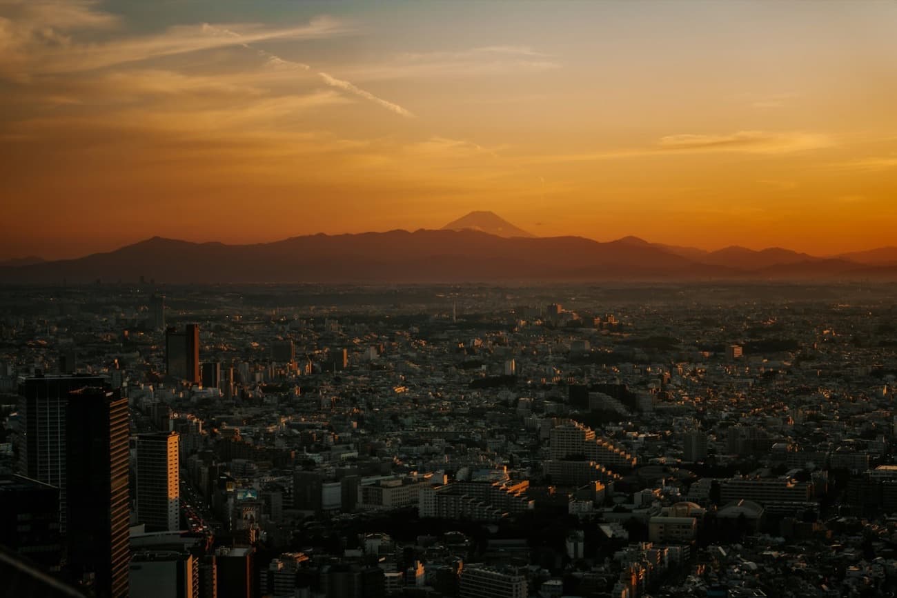 La metropoli infinita di Tokyo al tramonto, con il Monte Fuji che si staglia all'orizzonte tra la foschia dorata