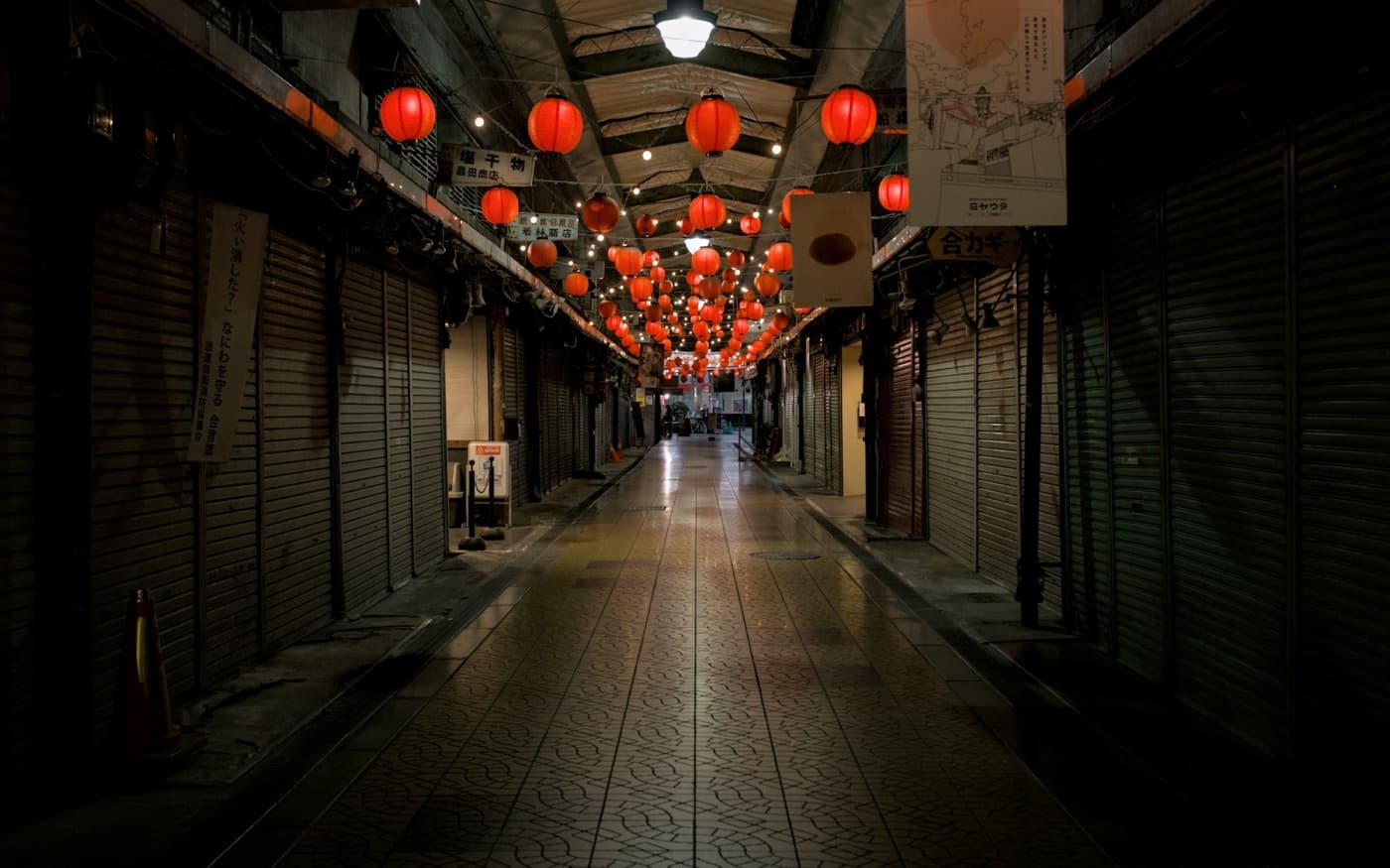 Una galleria commerciale giapponese di notte, con file di lanterne rosse accese sopra il vialetto deserto