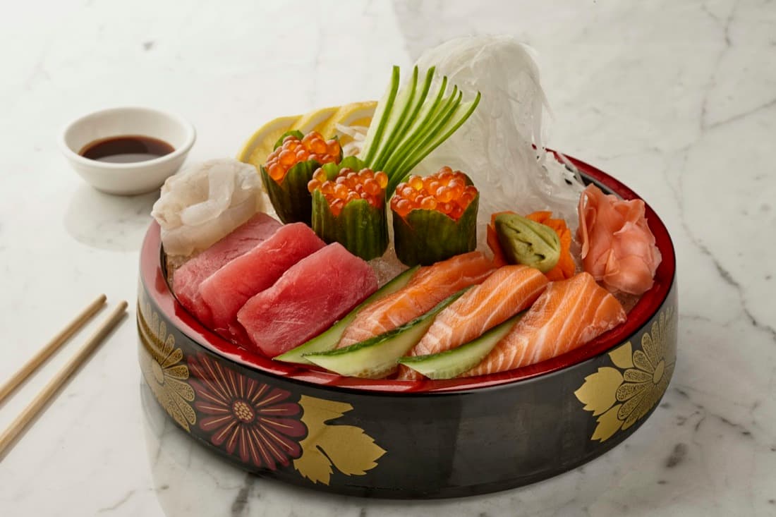 Un piatto di sashimi assortito servito in una ciotola laccata decorata a foglia d'oro