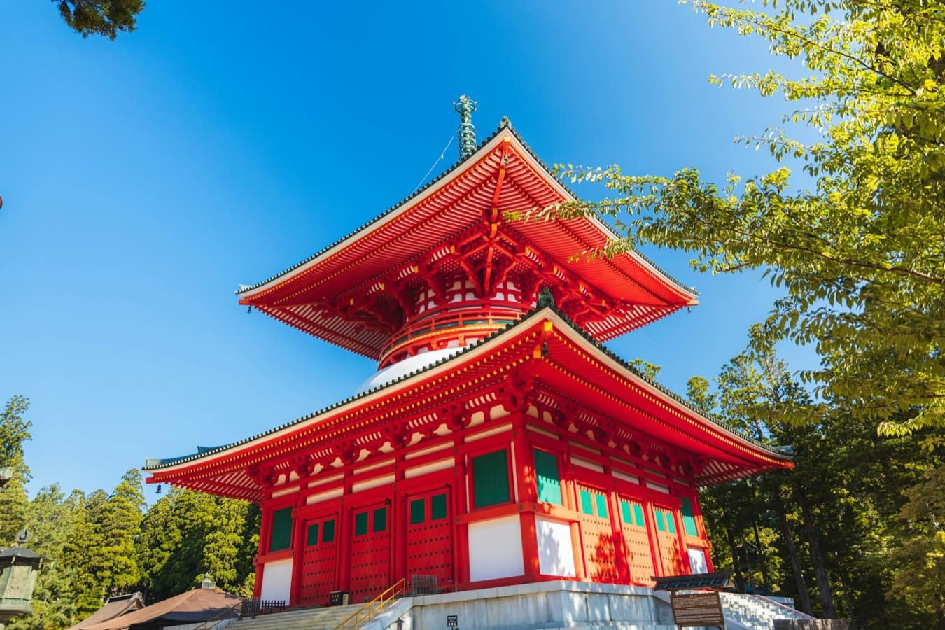 La grande pagoda vermiglia Konpon Daito di Koyasan, tra gli alberi sotto un cielo azzurro