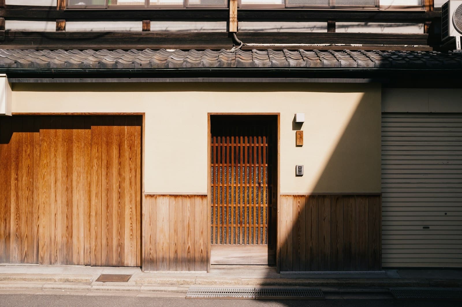 La facciata in legno di una machiya di Kyoto, con le grate di legno, la tenda noren all'ingresso e le piante in vaso