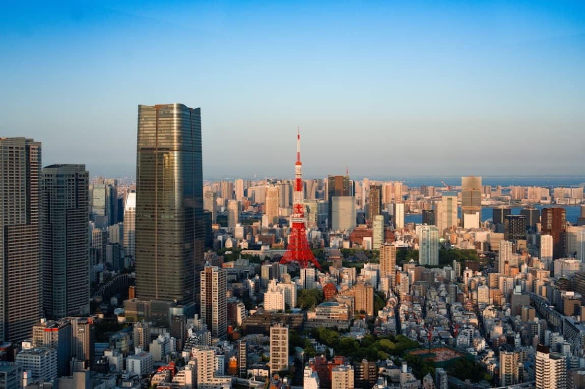 Il panorama di Tokyo dall'alto al tramonto, con la Tokyo Tower rossa che spicca tra i grattacieli fino alla baia