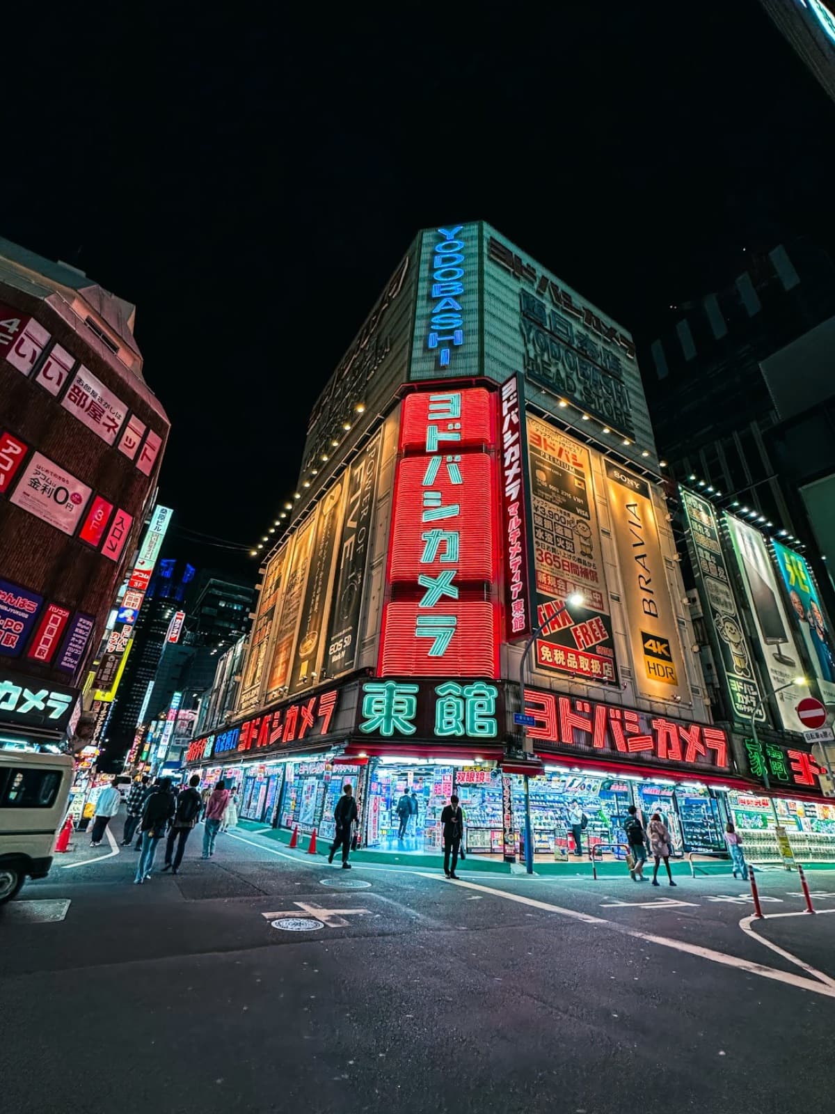 Il grande negozio di elettronica Yodobashi Camera a Tokyo di notte, con insegne al neon in giapponese
