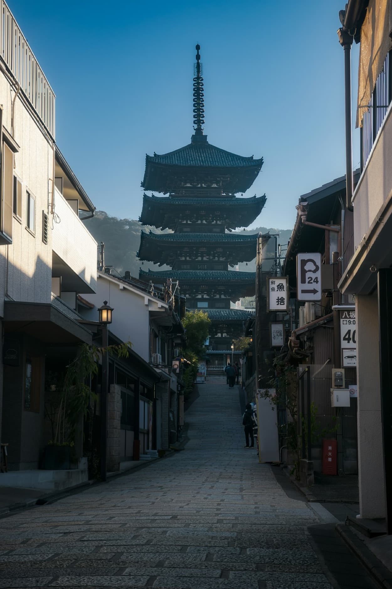 La pagoda di Yasaka che si staglia in fondo a una stradina tradizionale di Kyoto, sotto un cielo azzurro