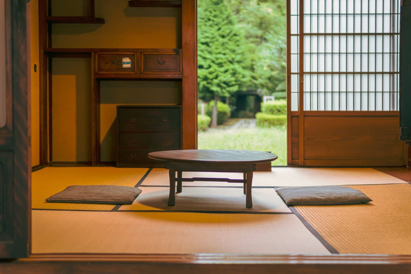 Una stanza tradizionale giapponese con tatami, tavolino basso di legno e le porte scorrevoli di carta aperte sul giardino