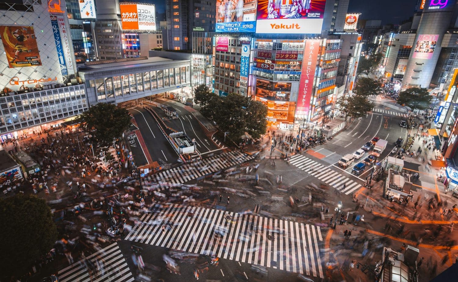 Lo Shibuya crossing di Tokyo di notte, visto dall'alto, con i neon e la folla che attraversa