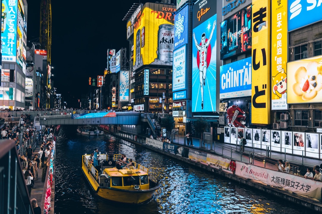 Le insegne luminose di Dotonbori riflesse nel canale, con la famosa pubblicità gigante del granchio