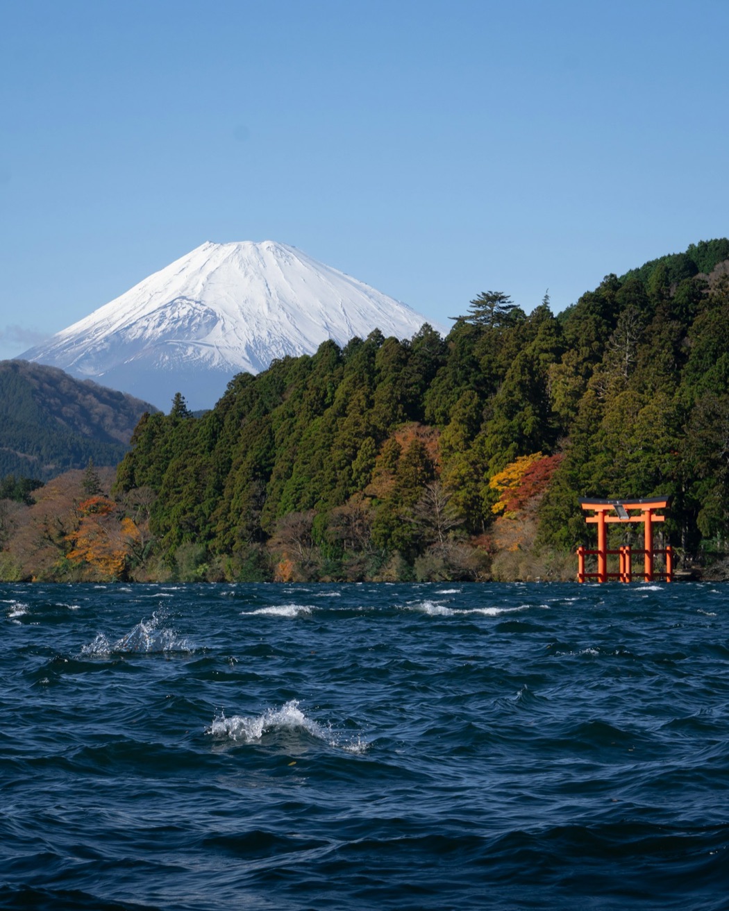 Il torii rosso sul lago Ashi di Hakone, con il monte Fuji innevato sullo sfondo