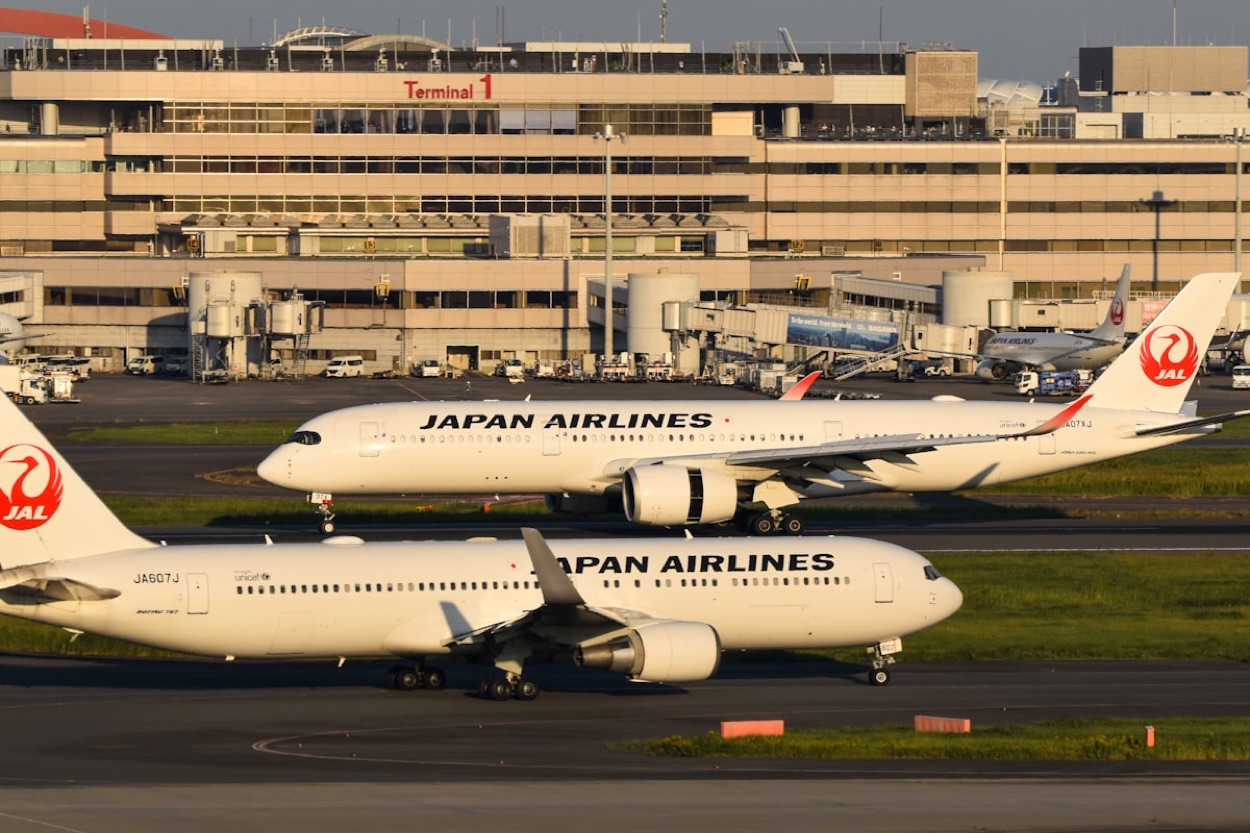 Due aerei di Japan Airlines sulla pista davanti al Terminal 1 di un aeroporto giapponese al tramonto