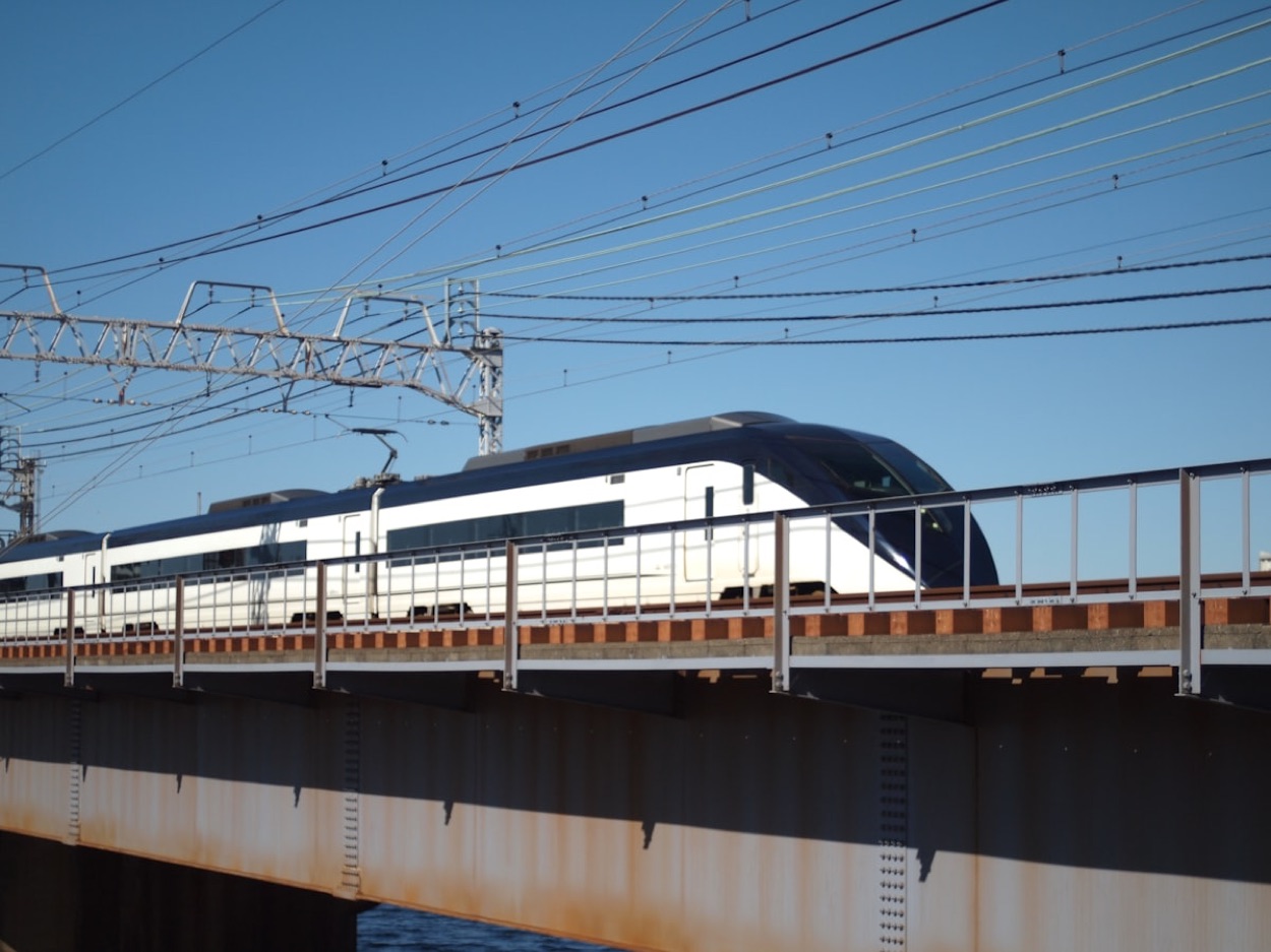 Un treno espresso bianco e blu per l'aeroporto attraversa un ponte sotto il cielo azzurro, in Giappone