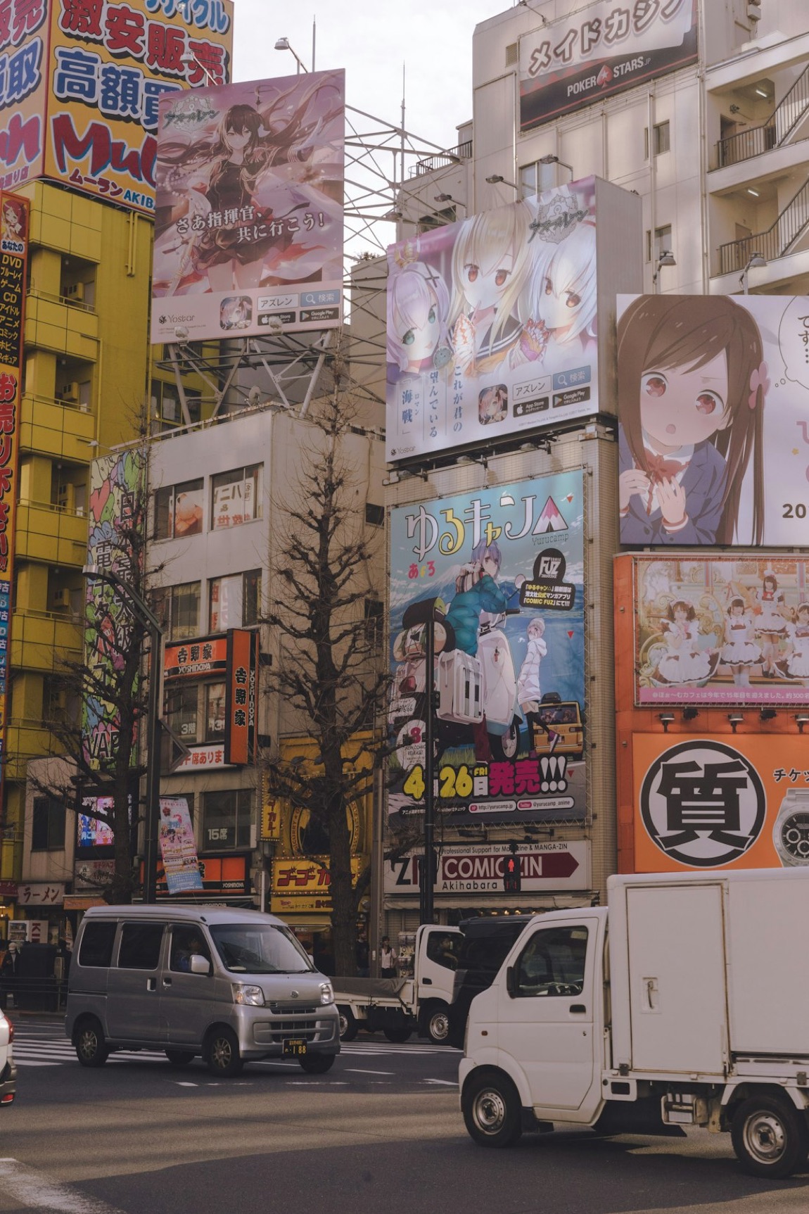Una via di Akihabara a Tokyo con enormi cartelloni di anime sui palazzi e insegne colorate