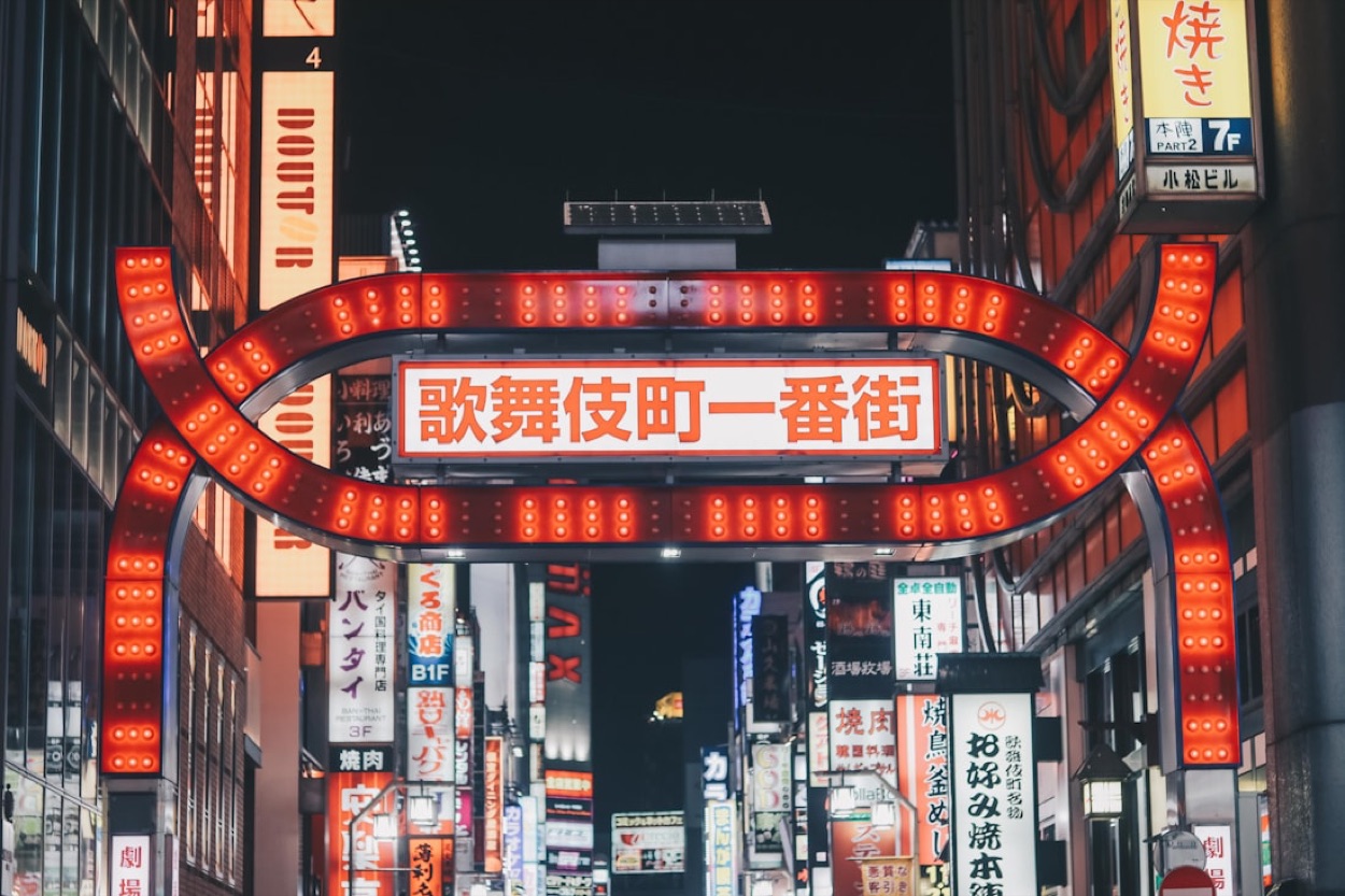 La grande insegna luminosa rossa all'ingresso di Kabukicho a Shinjuku, circondata da decine di insegne in giapponese