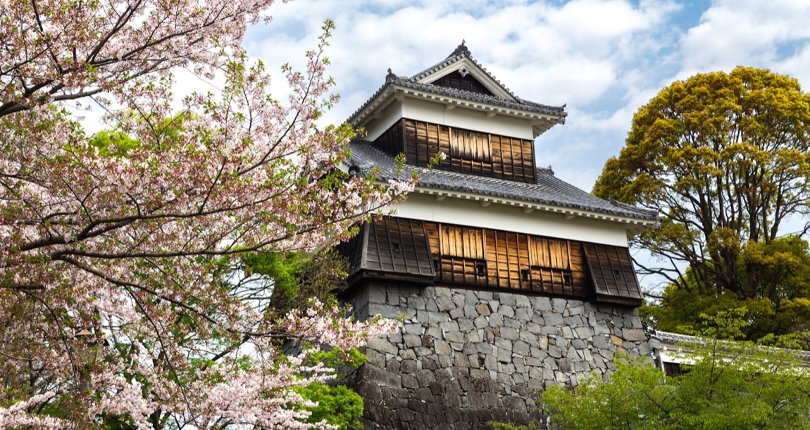 Veduta aerea del castello di Kumamoto con le mura di pietra e la città sullo sfondo, al tramonto
