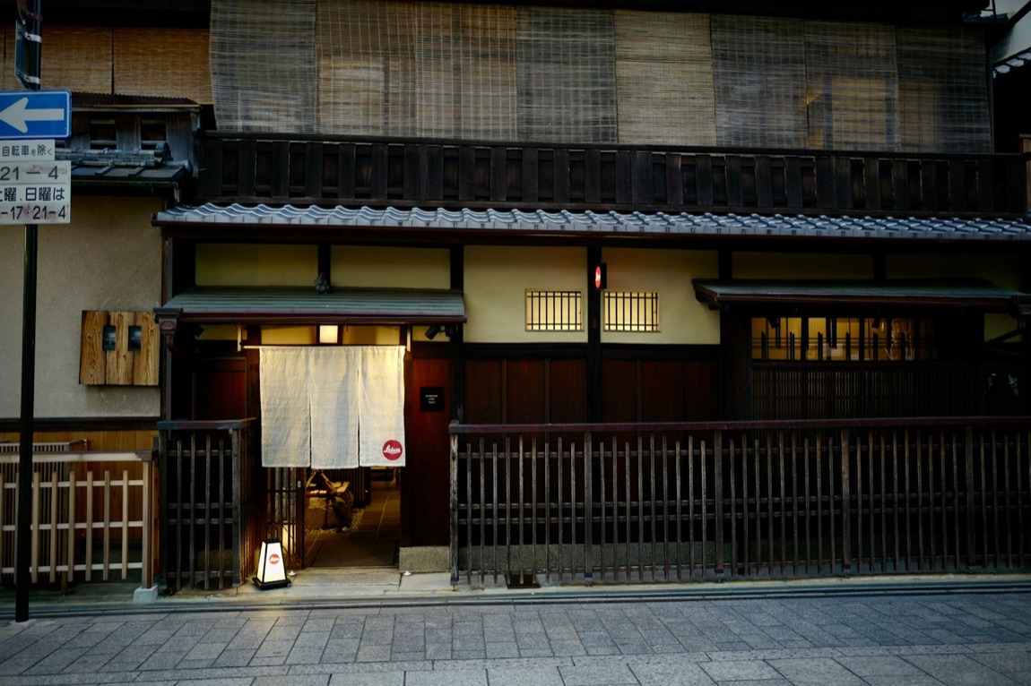 Una via di case da tè di legno a Gion, Kyoto, con lampioni e insegne tradizionali