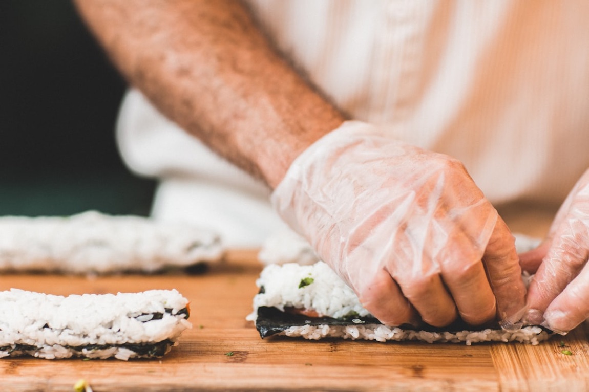Una persona che impara a fare sushi con un maestro in un corso di cucina giapponese