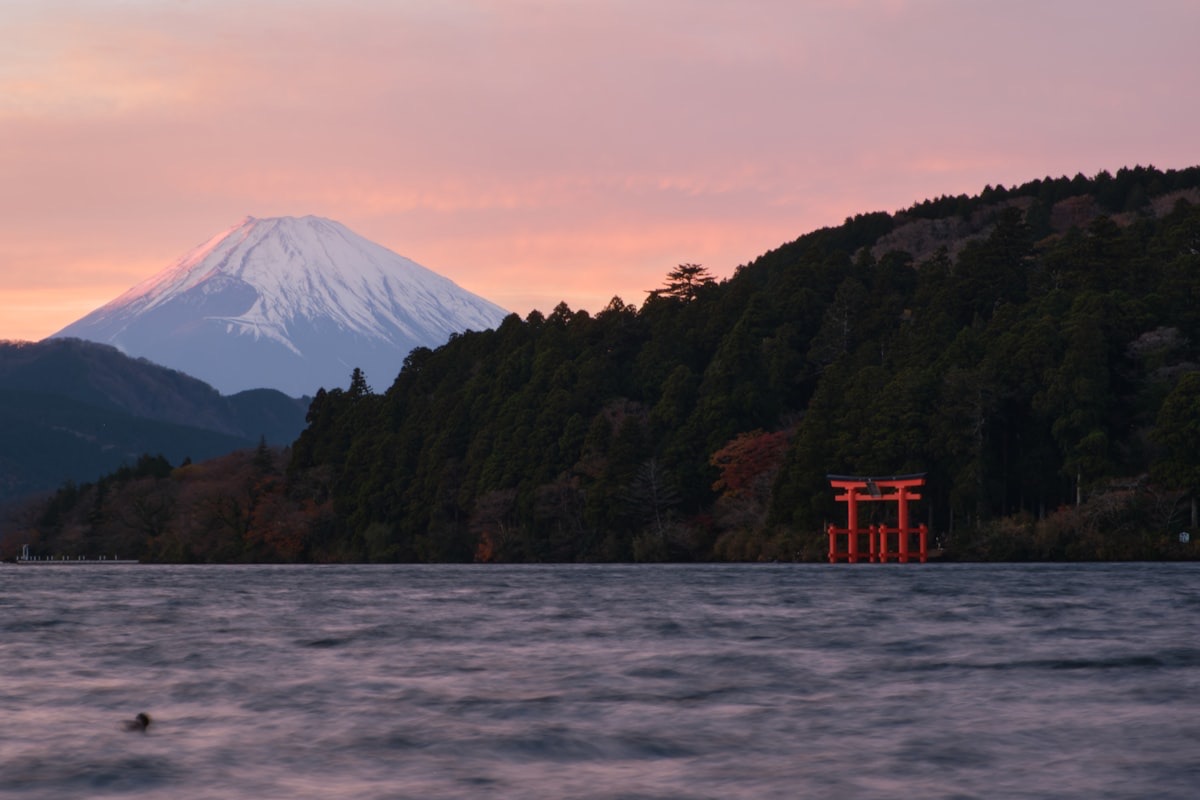Il lago Ashi al tramonto, con il Monte Fuji innevato e un torii rosso sulla riva