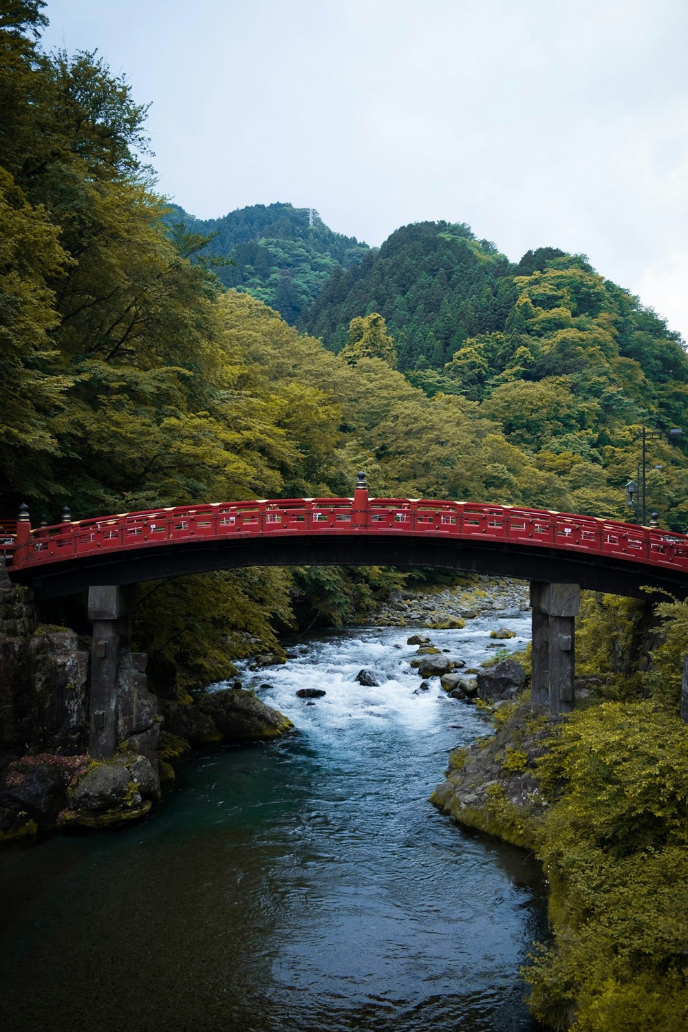 Il ponte rosso Shinkyo di Nikko sopra un fiume, tra le montagne verdi