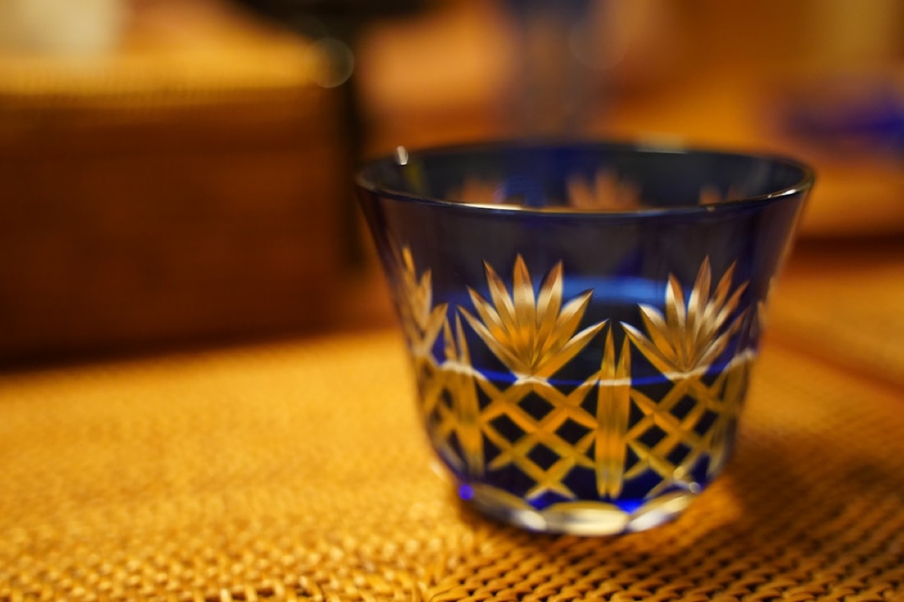 Una piccola coppa da sake di cristallo Edo kiriko blu cobalto, incisa a mano con motivi geometrici finissimi, su una stuoia