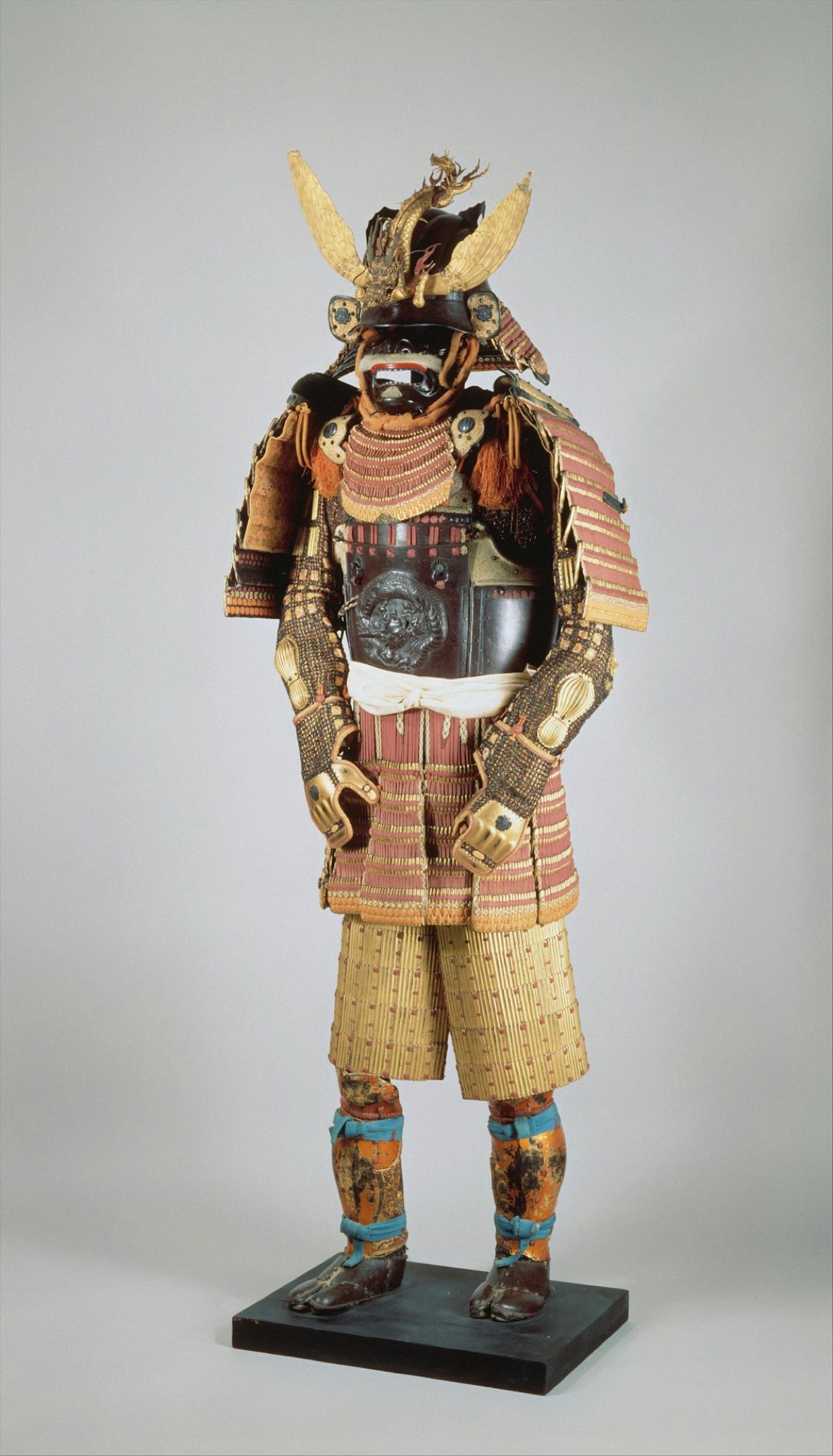 Un guerriero che indossa un'armatura da samurai completa, in posa con la spada, in uno spazio decorato con bandiere e lanterne