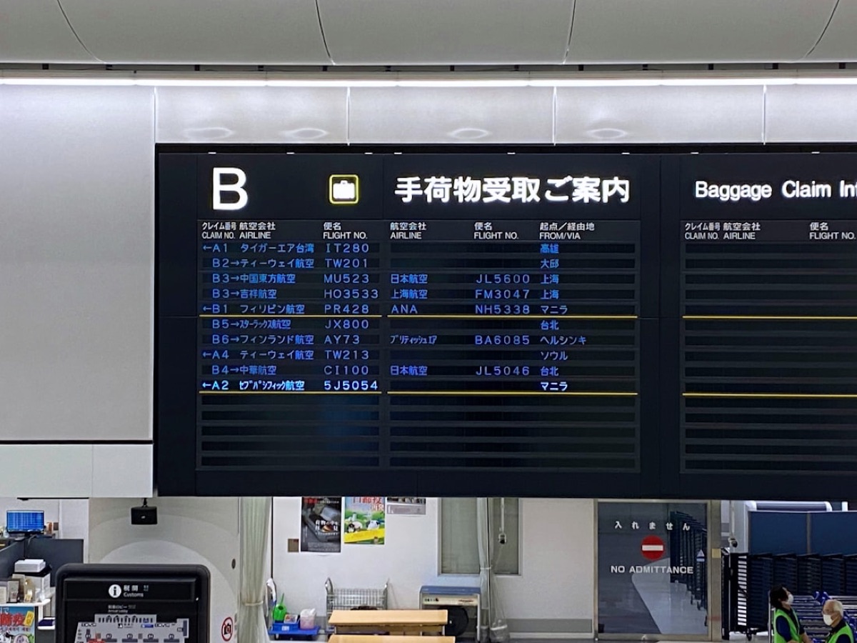 Il tabellone degli arrivi di un aeroporto giapponese, con scritte in giapponese e i nomi delle compagnie