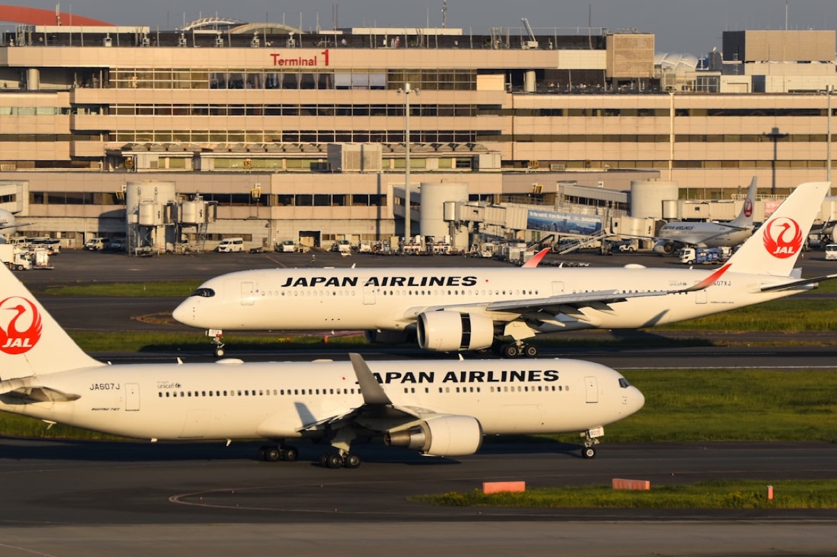 Due aerei di Japan Airlines sulla pista dell'aeroporto di Haneda, alla luce dorata del tramonto