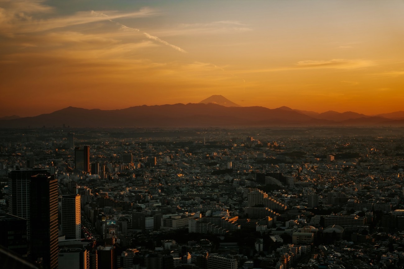 La metropoli infinita di Tokyo al tramonto, con il Monte Fuji che si staglia all'orizzonte tra la foschia dorata