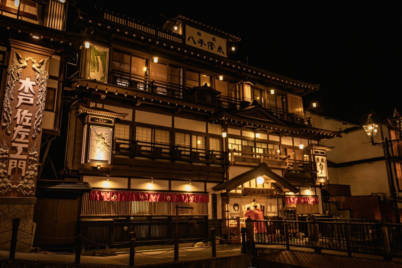 Le locande di legno illuminate di Ginzan Onsen la sera, lungo il fiume, con i lampioni a gas