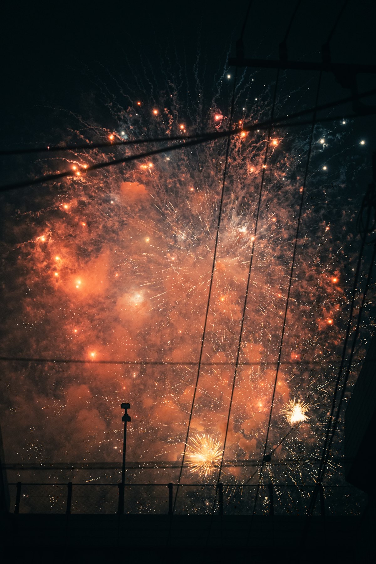 Fuochi d'artificio che riempiono il cielo notturno dietro i fili elettrici e i pali di una via giapponese