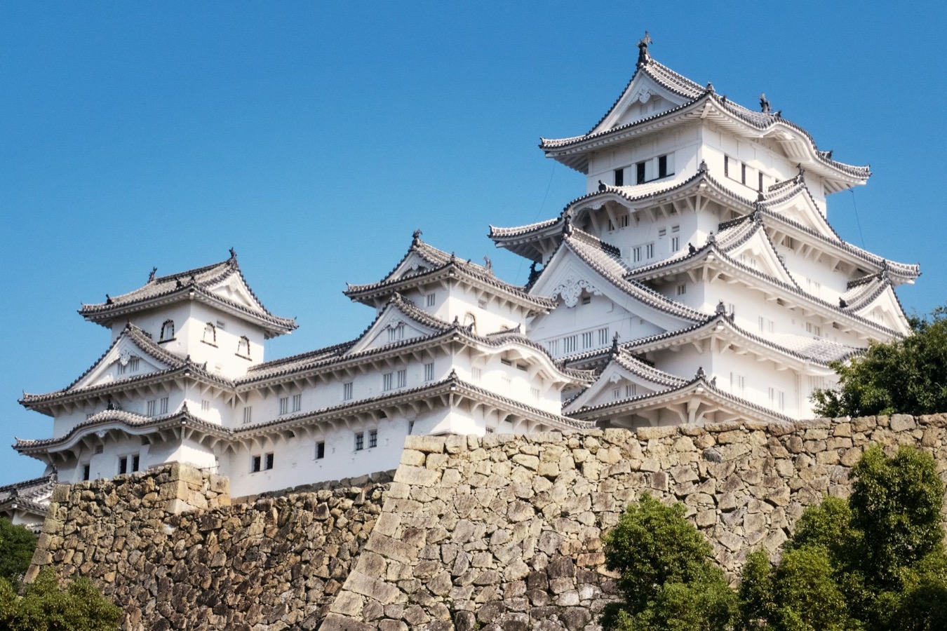 Il castello di Himeji, con i suoi tetti bianchi e le mura di pietra, sotto un cielo azzurro