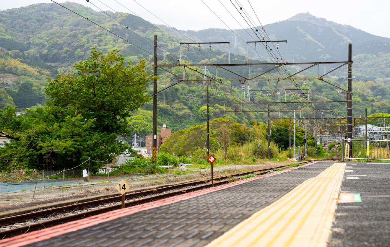 Un binario di una stazione di campagna in Giappone, con i monti verdi sullo sfondo e la banchina deserta