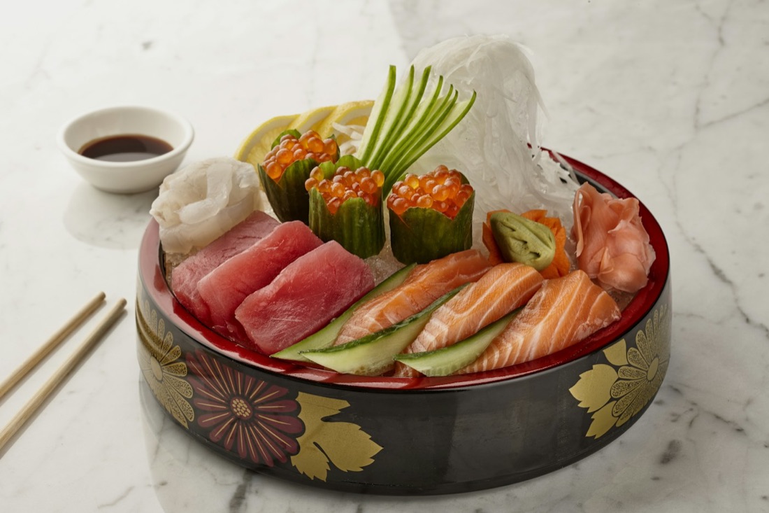 Un piatto di sashimi assortito servito in una ciotola laccata decorata a foglia d'oro