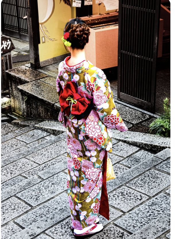 Una donna in kimono tra le case da tè di legno