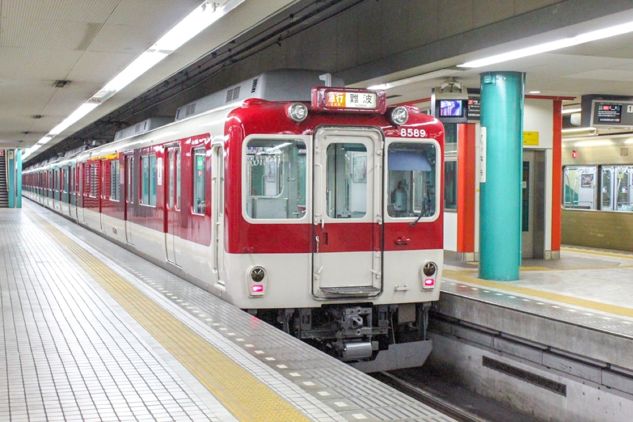 Un treno del Kansai fermo al binario di una stazione, con la destinazione in giapponese e la banchina vuota