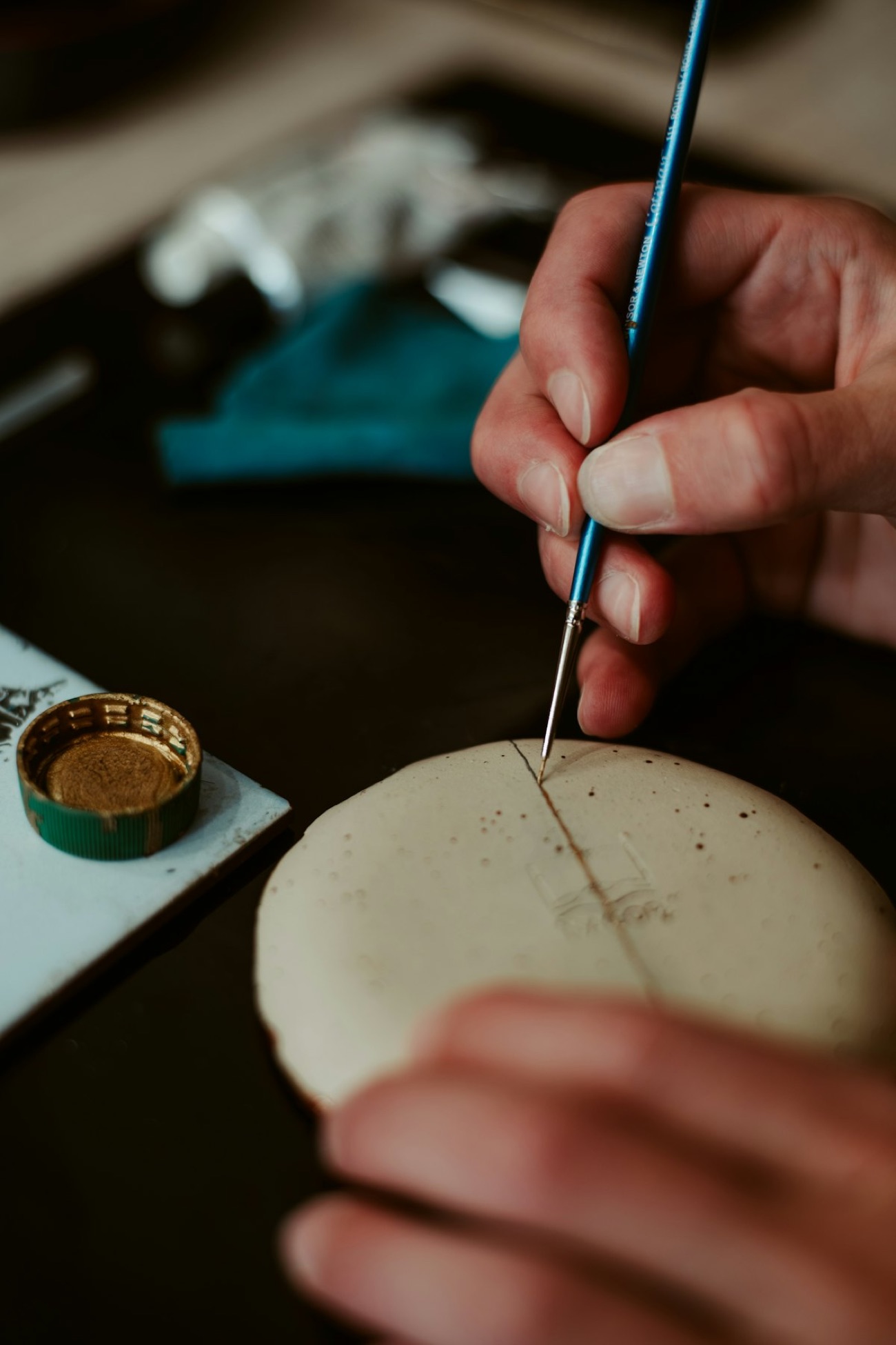 Un'artigiana al lavoro su un pezzo di lacca, con il pennello sottile e la lacca nera lucida
