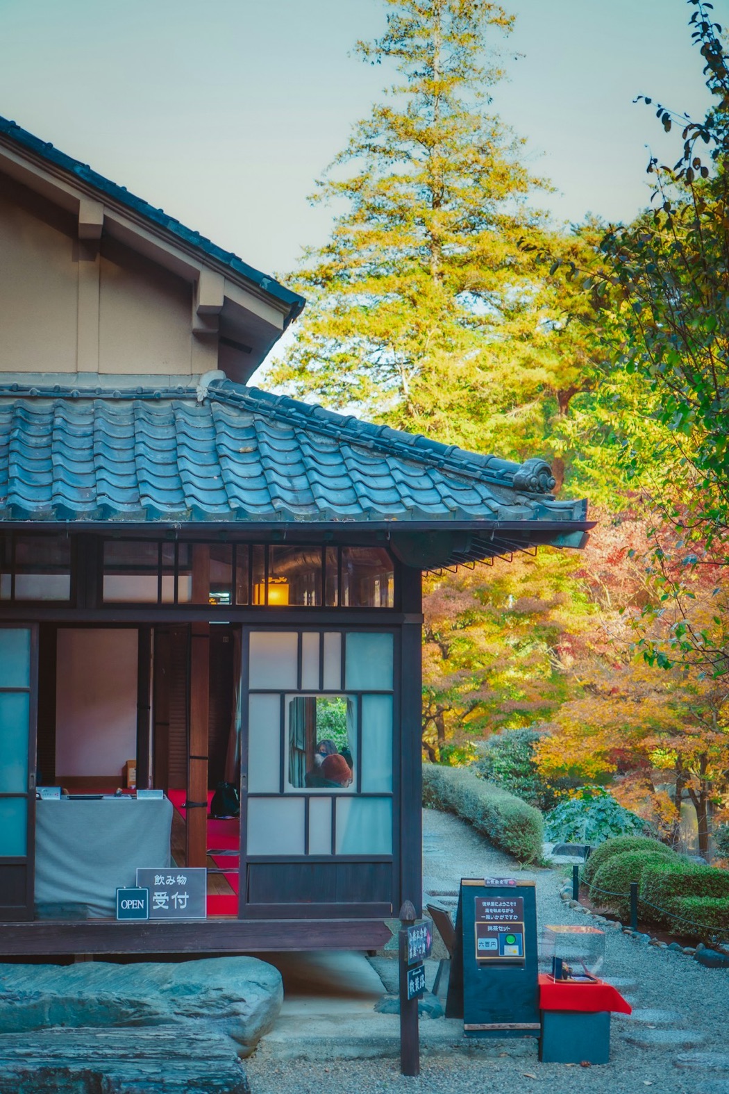 Una tradizionale sala da tè giapponese in legno con tetto di tegole, tra gli aceri d'autunno, con l'insegna "matcha set"