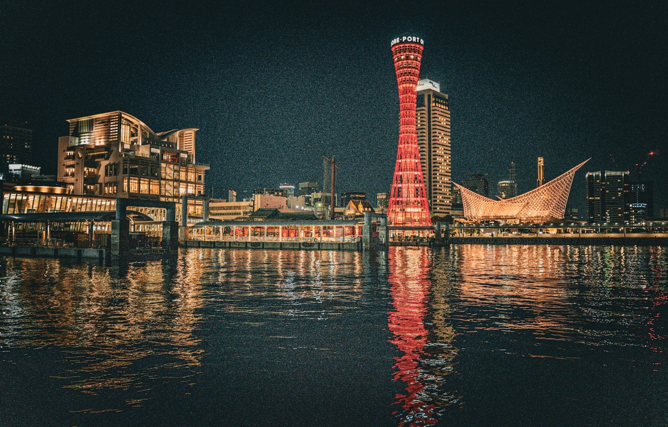 La torre rossa del porto di Kobe illuminata di notte, con il riflesso sull'acqua