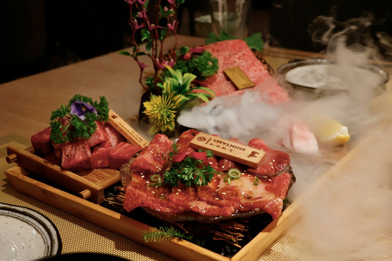 Carne di manzo wagyu marezzata servita su un vassoio di legno, con vapore e guarnizioni