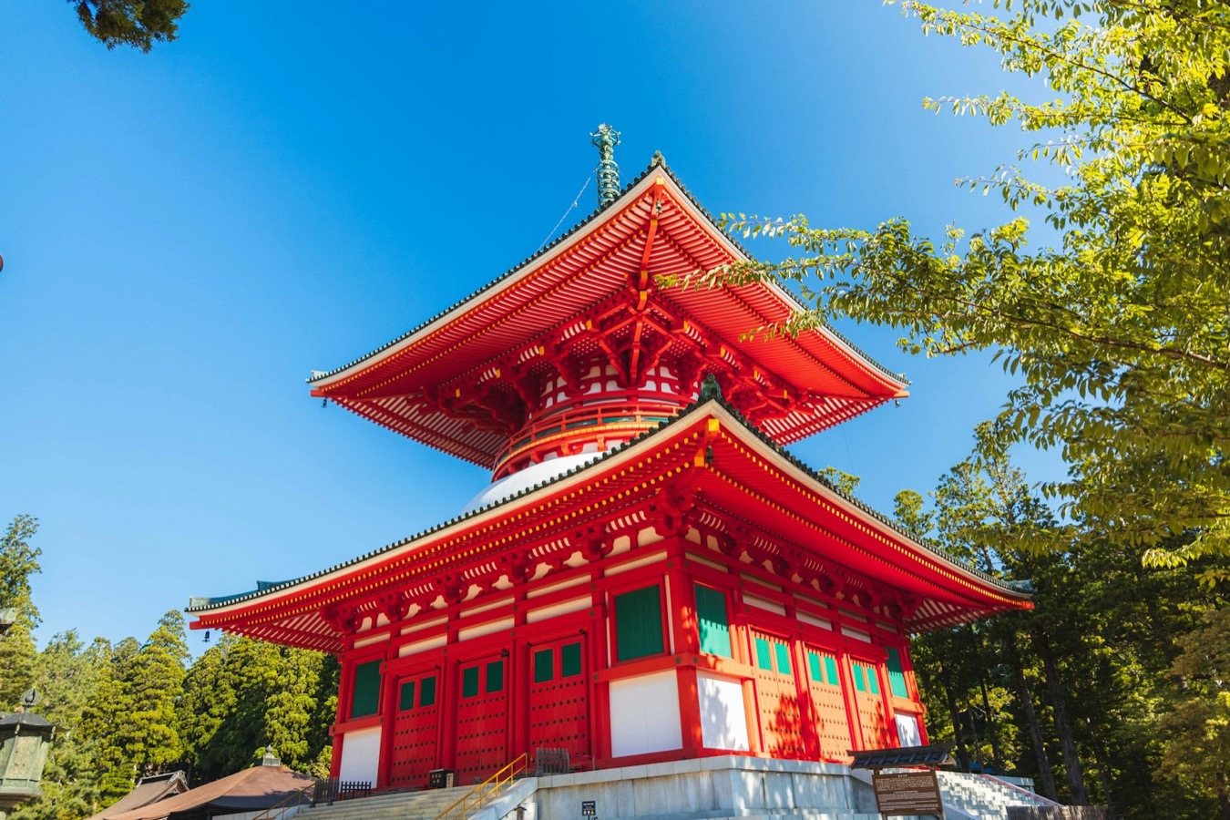 La grande pagoda vermiglia Konpon Daito di Koyasan, tra gli alberi sotto un cielo azzurro