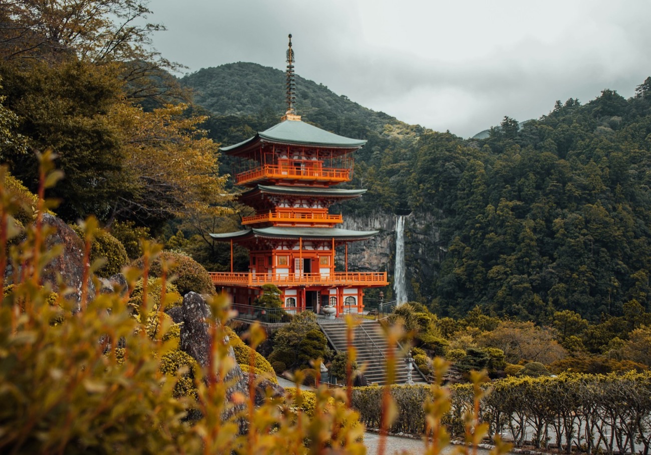 La pagoda vermiglia di Seiganto-ji con la cascata di Nachi che scende dalla montagna verde alle sue spalle
