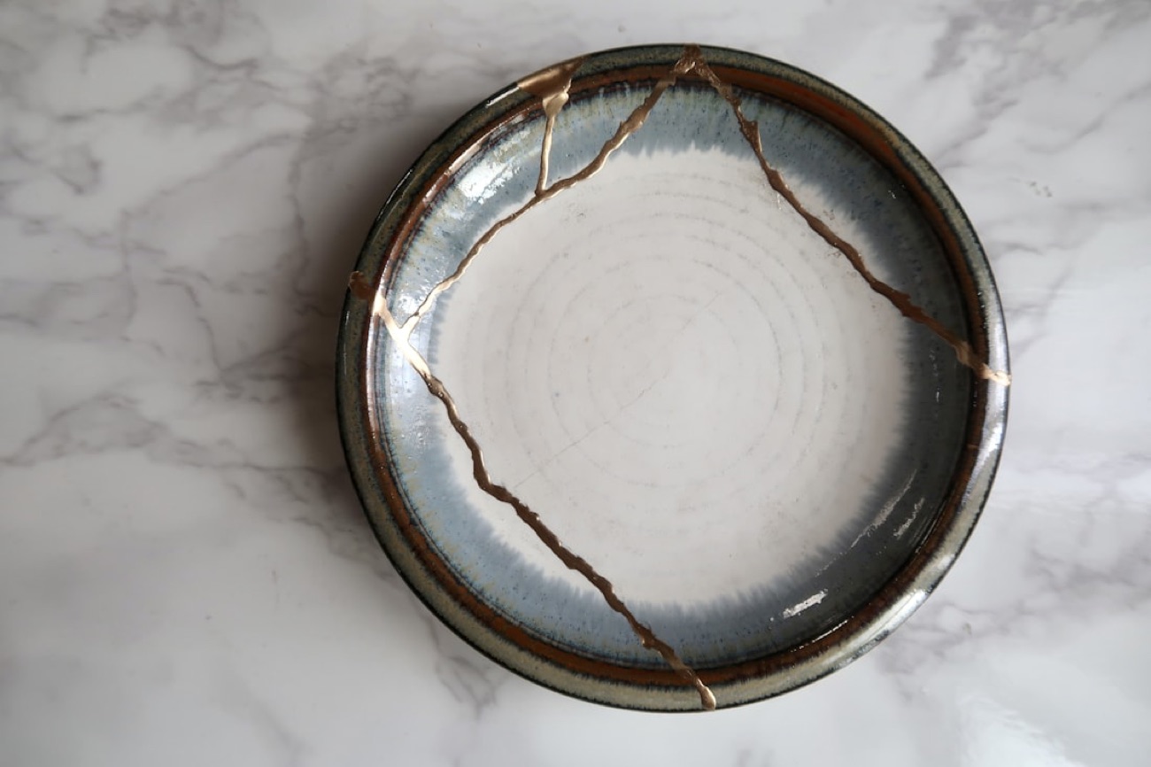 Un piatto di ceramica riparato con il kintsugi, con le crepe saldate da vene d'oro che lo attraversano