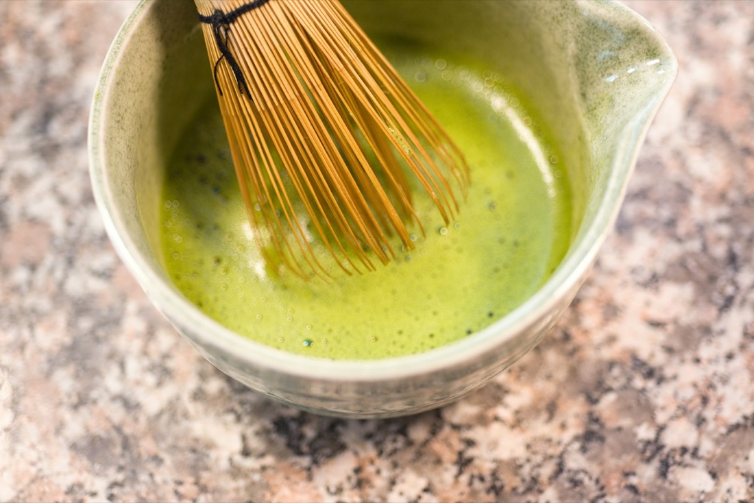 Una ciotola di matcha verde brillante appena preparato con il frustino di bambù chasen